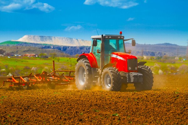 Brand new red tractor on the field working on land
